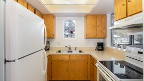 A kitchen with wooden cabinets, a white refrigerator, a double sink, and a stove. - Outpost: Pitchfork 2106 - Walk to Town Square! (Jackson)