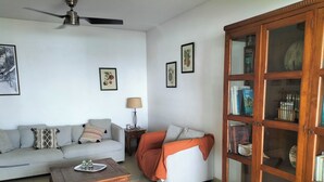 Ein Wohnzimmer mit einer Couch, einem Couchtisch, einem Schrank und einem Deckenventilator.