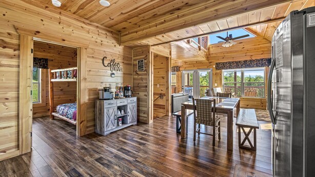 Ein Holzblockhaus-Interieur mit Küche, Essbereich und einem Bett.