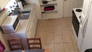 A compact kitchen with a microwave, sink, and stove. There is a small dining table with chairs. - Casa Colorado: Cozy. Cute. Convenient. (Colorado Springs)