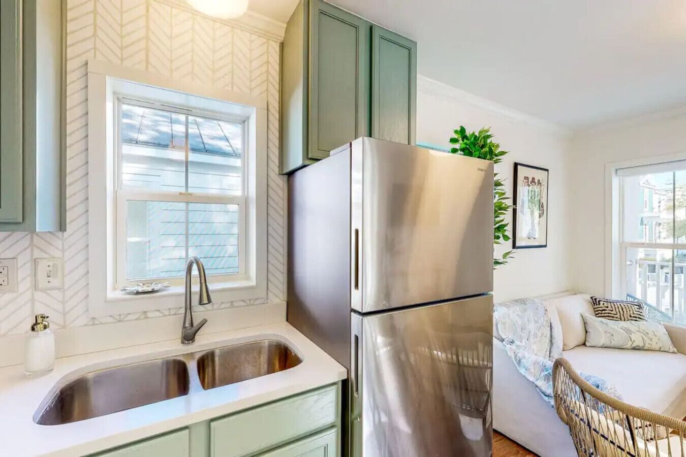 Cocina compacta con refrigerador de acero inoxidable, pileta doble y ventana con persianas.