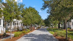 A residential street lined with single-family homes, a gravel driveway, and well-maintained landscaping. - Picture book cottage! (Ocean Springs)