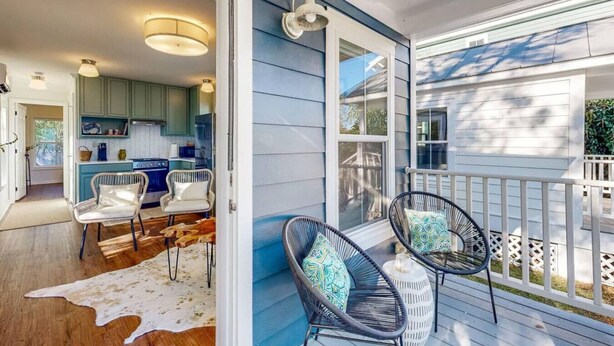 A covered porch with wicker chairs and a cowhide rug. - Picture book cottage! (Ocean Springs)