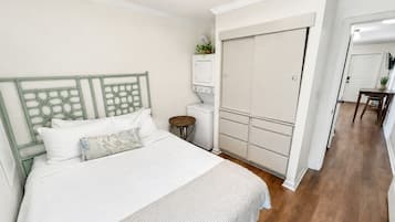 Un dormitorio con cama, armario, mesita y espejo.