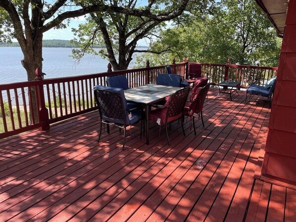 Une terrasse en bois, agréée de mobilier d’extérieur, qui offre une vue sur une étendue d’eau.