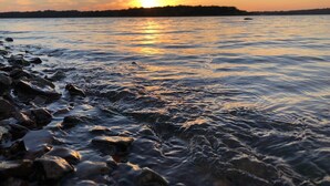 A sunset over a calm body of water with rocks in the foreground. - Eufaula Lake front access w/wraparound deck and spectacular views! Pet friendly! (Checotah)