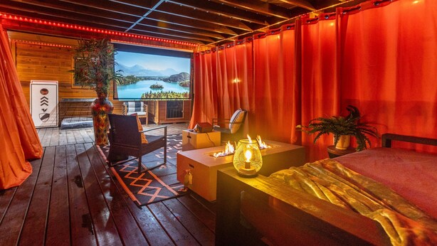 A cozy room with a bed, a desk, a chair, a TV, and a view of a lake. - Romantic|Private|Wellness|OutdoorMovieNight (Broken Bow)