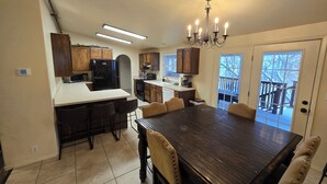 A spacious kitchen with a central island, wooden cabinets, and a chandelier.