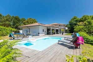 Un área de piscina con sillones de descanso y una terraza de madera.
