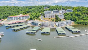 Un hôtel situé au bord d’un lac, composé de plusieurs bâtiments, avec des bateaux amarrés et une colline boisée.