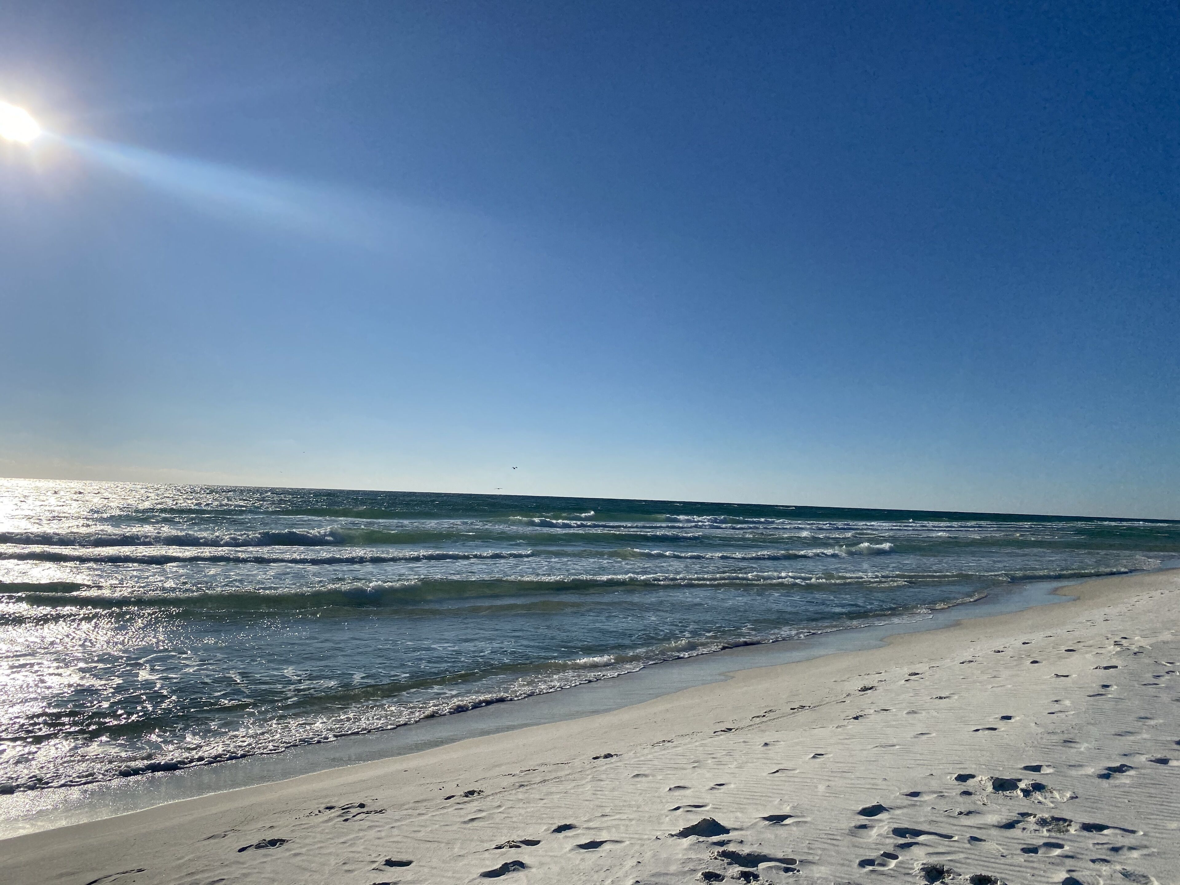 A beach with footprints in the sand and a clear sky.