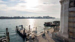 A waterfront view with a pier, a large column, and a distant city skyline. - Ve.N.I.Ce. Cera Tintoretto Suite (Venezia)
