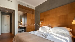 A hotel room with a large bed, a desk, and a chair.