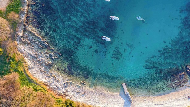 An aerial view of a coastal area with clear turquoise waters, rocky shorelines, and boats. - Holiday apartment Beach apartment Petra (Pula)