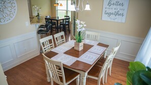 A dining area with a wooden table, white chairs, and a vase of flowers. There is a mirror on the wall and a sign that says "Better when we are together." - Craftsman ranch (Lawrenceville)