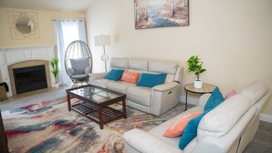 A living room with a fireplace, a sofa set, a coffee table, and a painting on the wall. - Craftsman ranch (Lawrenceville)