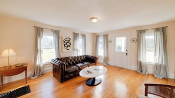 A spacious living room with a leather sofa, a round coffee table, and a wooden floor.