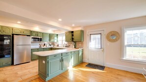 A kitchen with green cabinets, a stainless steel refrigerator, a microwave, and a sink. - < 4 Mi to Cooperstown: Charming Historic Home! (Fly Creek)