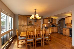 Une cuisine moderne avec des meubles de rangement en bois, une table à manger avec des chaises et un lustre.