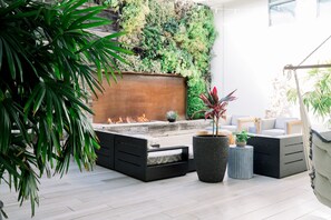A modern outdoor seating area with a fire feature, a vertical garden wall, and a hanging chair. - SCP Seven4One (Laguna Beach)