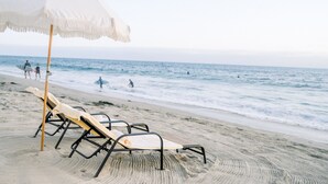 Une plage avec des chaises longues et un parasol.