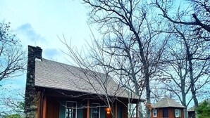 Un chalet rustique doté d’une terrasse en bois, d’une cheminée et d’un petit porche.