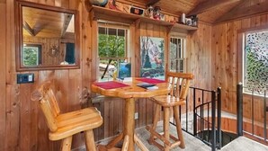 L’intérieur d’un chalet en bois, avec une table en bois et deux chaises, un globe terrestre et un tableau représentant un paysage de montagne.