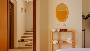 Ein Hotelzimmer mit einem Bett, einer Holzablage mit Handtüchern, einem Spiegel und einer Treppe.