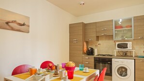 Eine moderne Küche mit Holzausbau, einer Mikrowelle, einer Waschmaschine und einem Essbereich mit einem für das Frühstück gedecktem Tisch.