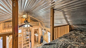 A compact, rustic cabin with a sloped ceiling, wooden walls, a lofted sleeping area, and a small kitchenette. - Lakefront Cabin w/ 2 Lofts, Boats on 4 Acres (Winnsboro)