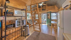 A cozy cabin interior with a wooden interior, a loft area, and a kitchenette. - Lakefront Cabin w/ 2 Lofts, Boats on 4 Acres (Winnsboro)