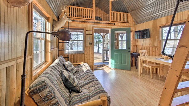 A cabin with a loft bedroom, a dining area, and a large window. - Lakefront Cabin w/ 2 Lofts, Boats on 4 Acres (Winnsboro)