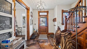 A wooden staircase with a chandelier, a door with a glass panel, and a rug on the floor. - The Pendleton Lodge-8 bedrooms/3baths-heart of COS (Colorado Springs)