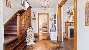 A wooden staircase with a chandelier, a fur rug, and antler decorations. - The Pendleton Lodge-8 bedrooms/3baths-heart of COS (Colorado Springs)