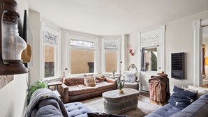 A cozy living room with a large window, a fireplace, and a comfortable seating area. - The Pendleton Lodge-8 bedrooms/3baths-heart of COS (Colorado Springs)