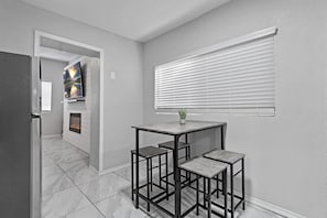 A modern kitchen with a marble floor, a built-in fireplace, and a dining area with a table and two chairs.