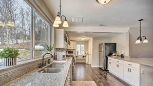 A modern kitchen with granite countertops, stainless steel appliances, and a large window providing a view of the outdoors. - A-Frame Cabin w/ Hot Tub: 5 Mi to Waterford! (Melrose)