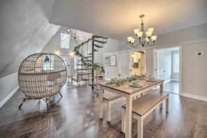 Een eetgedeelte met een houten tafel, een bank en een wenteltrap.