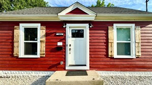 A red building with two windows, a white door, and a mailbox. - Lansing 3BR near downtown — Game room & EV garage (Lansing)