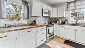 A modern kitchen with white cabinets, a stainless steel oven, and a microwave. - Lansing 3BR near downtown — Game room & EV garage (Lansing)