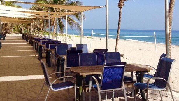 A beachside café with outdoor seating under canopies, overlooking the ocean. - Casa Trebol (Tela)