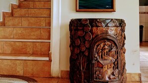 A staircase with a handrail, a painting of a tropical beach, and a carved wooden cabinet. - Casa Trebol (Tela)