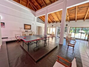 A spacious indoor area with a ping pong table, wooden beams, and large windows. - Casa de Campo Luxury Villa w/pool and 5 bedrooms! (La Romana)