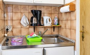 Una cocina con cafetera, hervidor y escurreplatos.