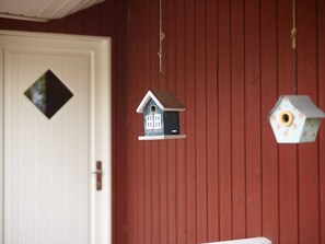 A red barn with two birdhouses hanging from the ceiling.