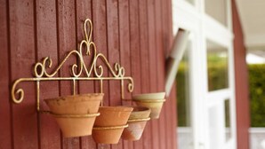 En röd vägg med en metallkonsol som används som dekoration och som håller upp terrakottakrukor.