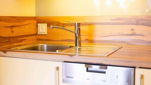 Une cuisine dotée d’un évier en acier inoxydable, d’un dosseret en bois et d’un lave-vaisselle encastré.