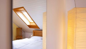 Une chambre avec un puits de lumière, une tête de lit en bois et une lampe de chevet.