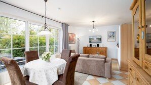 A dining area with a round table, chairs, and a view of greenery outside. - (BIR9a) Apartment Vahle 1 - Apartment "Vahle 1" up to 4 persons ( (Timmendorfer Strand)