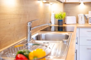 Eine moderne Küche mit Spüle aus Edelstahl, einem Wasserhahn und einer Arbeitsplatte mit Pflanze und Obstschale.